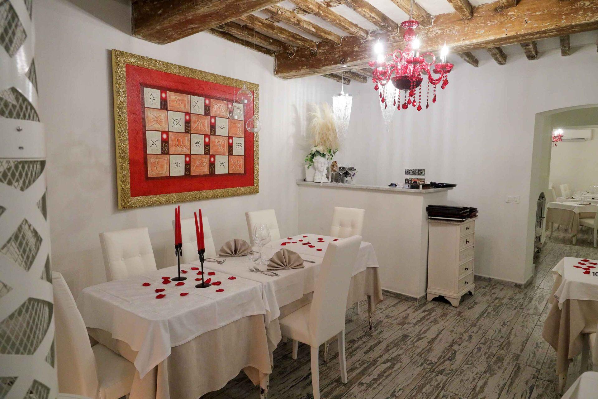 Romantic restaurant interior with white tables and red decorations on the ceiling and wall.